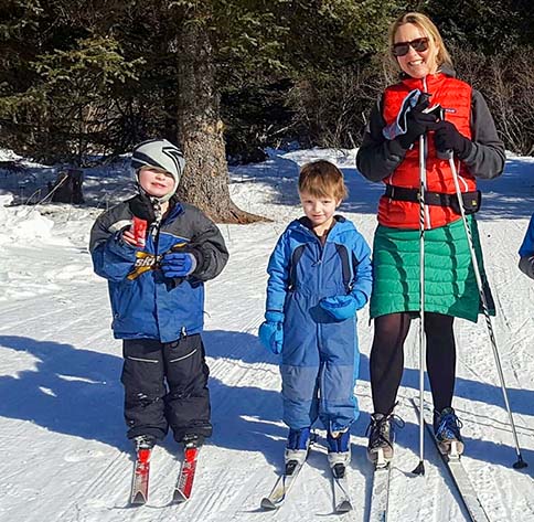 woman and kids cross country skiing together